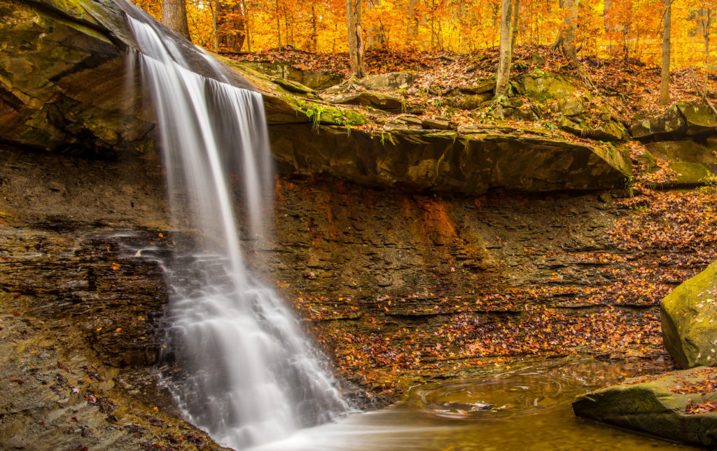 Cascada inconjurata de frunzis portocaliu de toamna si frunze cazute in Parcul National Cuyahoga Valley, Ohio